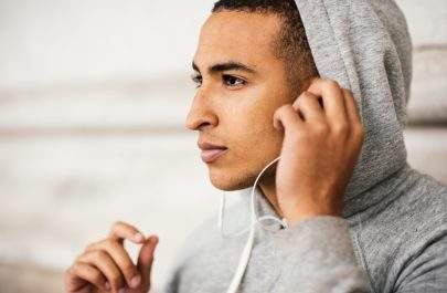 Male runner wearing grey hoody listening to earphone music