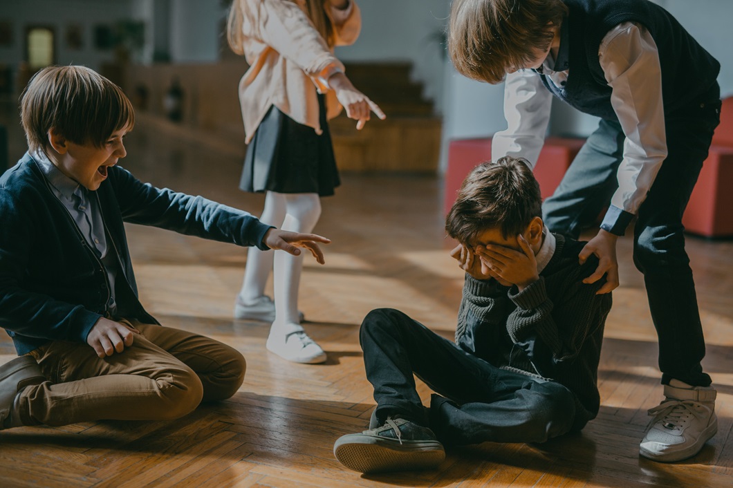 Bullying. Photo by Mikhail Nilov: https://www.pexels.com/photo/children-finger-pointing-at-a-boy-sitting-on-a-wooden-floor-7929446/